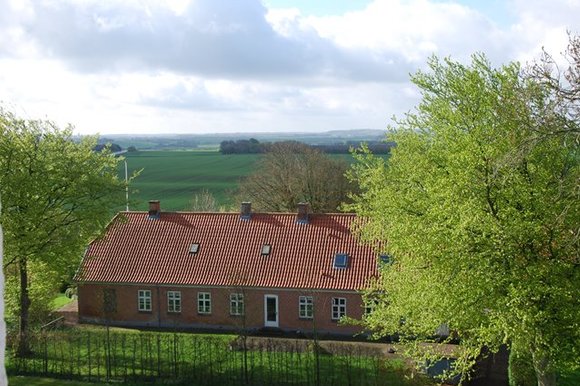 En præstegård beliggende i grønne omgivelser med træer rundt om