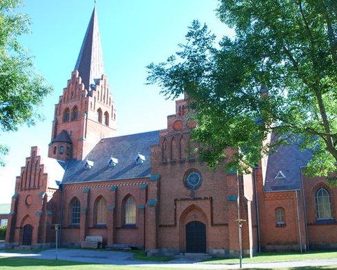 Nykøbing kirke med træer med grønne blade i forgrunden